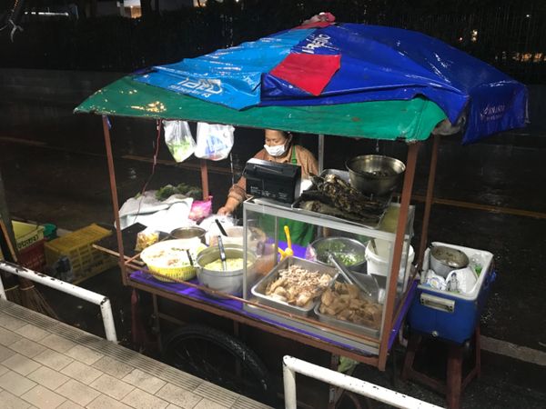 タイ「「バンコク 弾丸」の巻」の写真：大雨の中、通りの屋台ではオバチャンが料理...